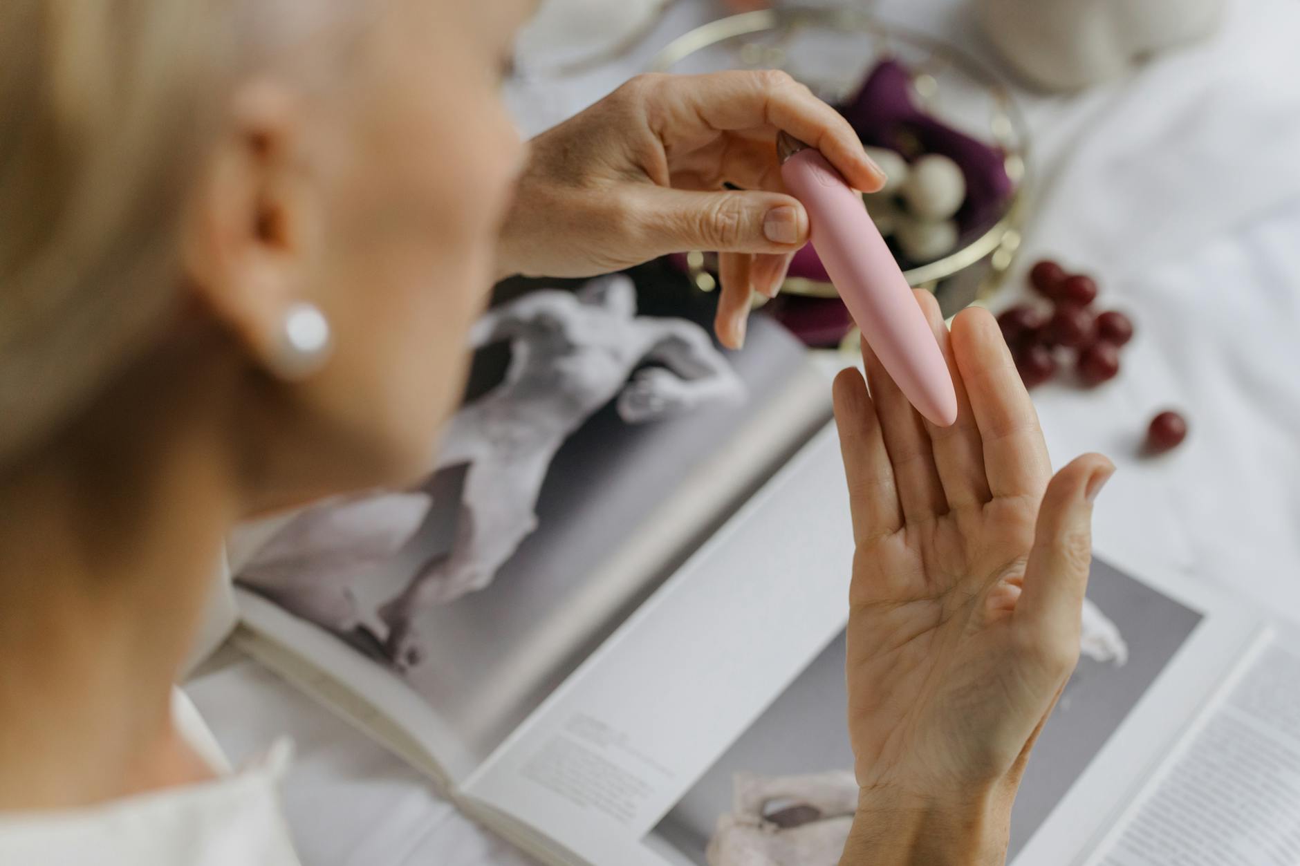 Woman with eyeglasses holding blue and pink silicone vibrators in a contemplative manner