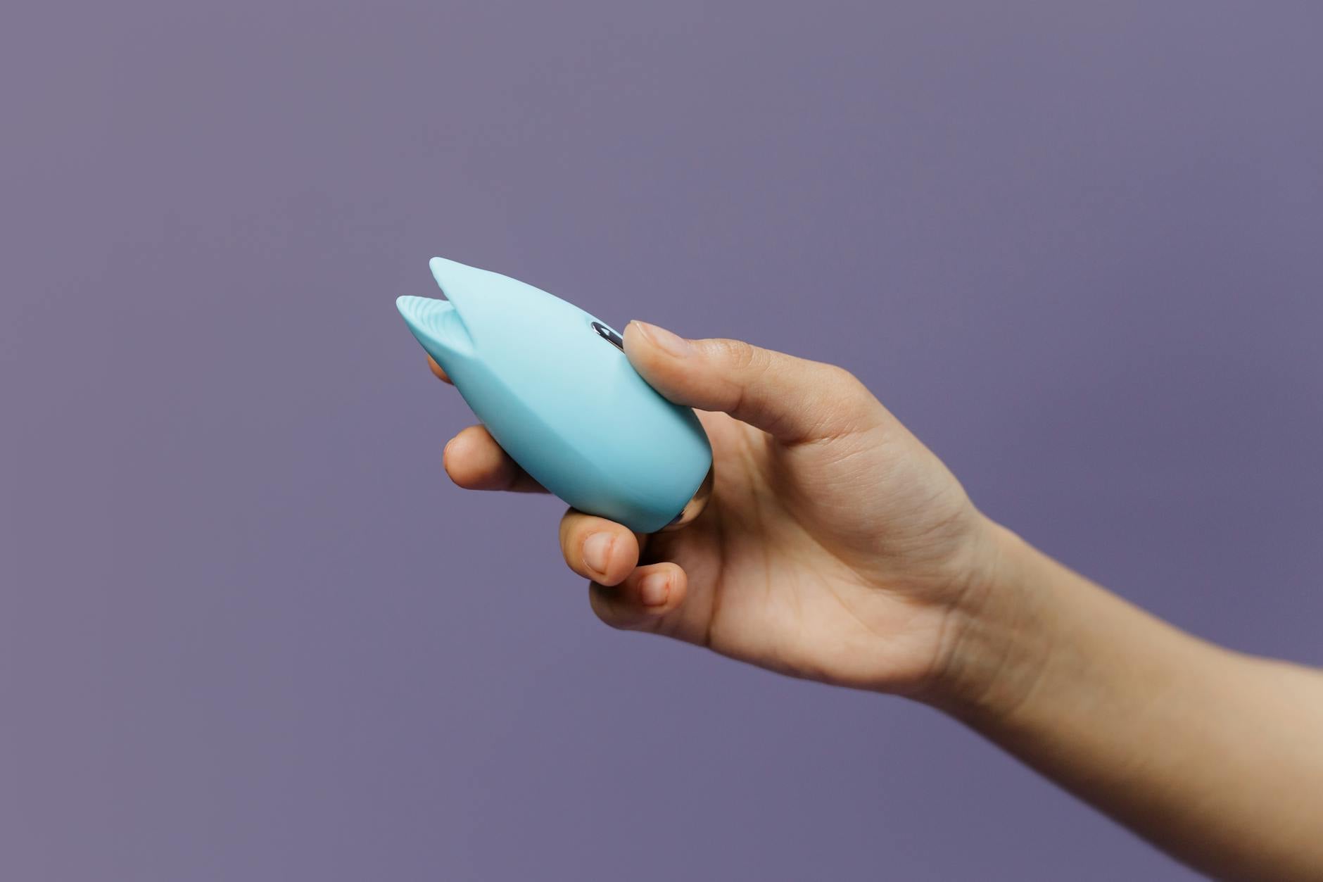 Bright yellow vibrator surrounded by fresh lemons on a warm yellow background