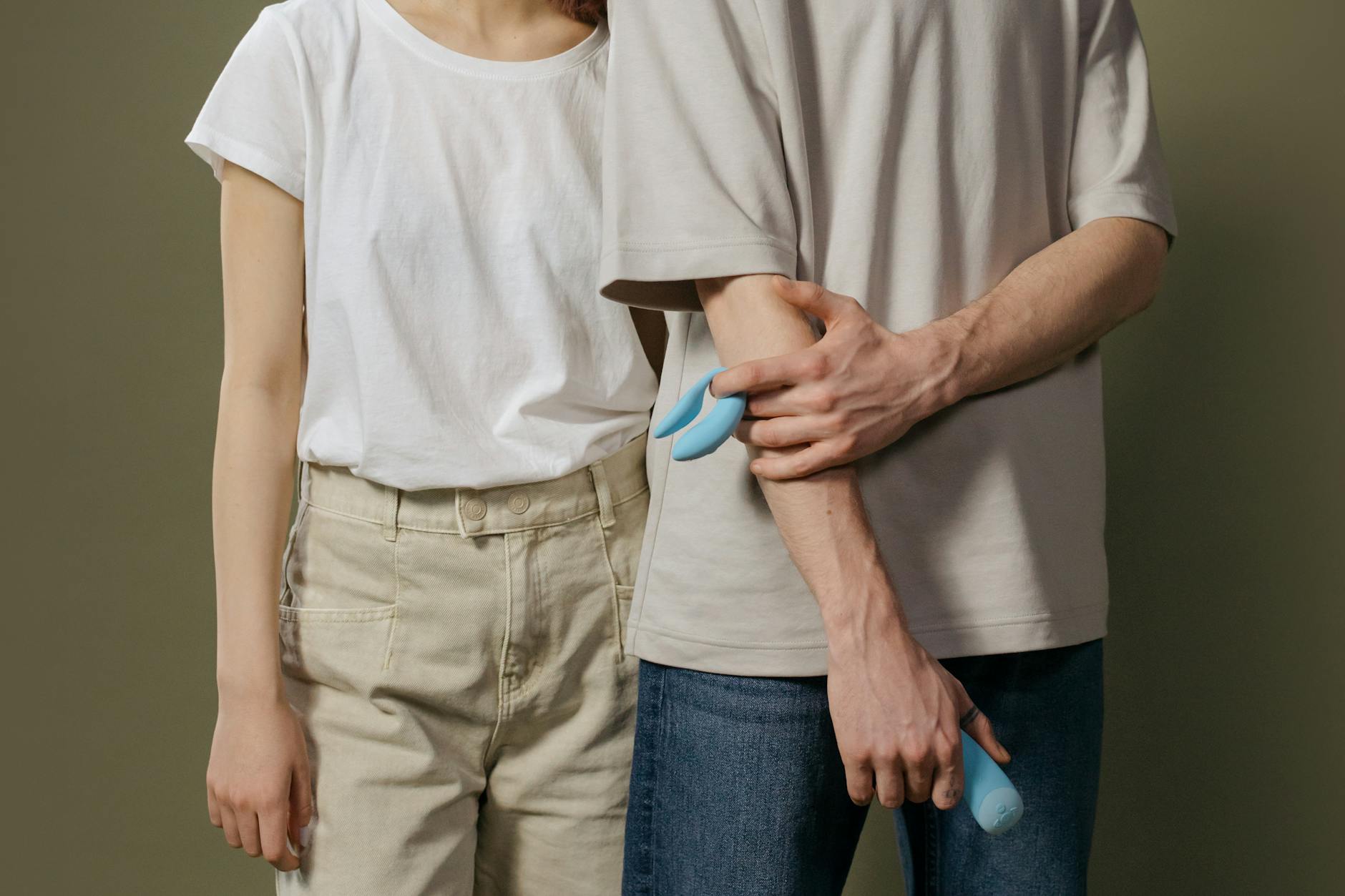 Close-up of a hand holding an orange vibrator against a minimalistic purple backdrop
